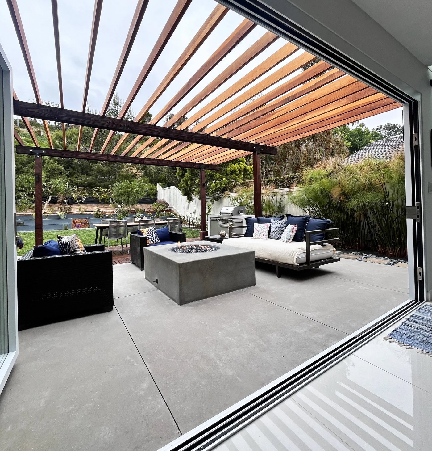 Caroline project — redwood pergola over concrete fire pit lounge and built-in outdoor kitchen