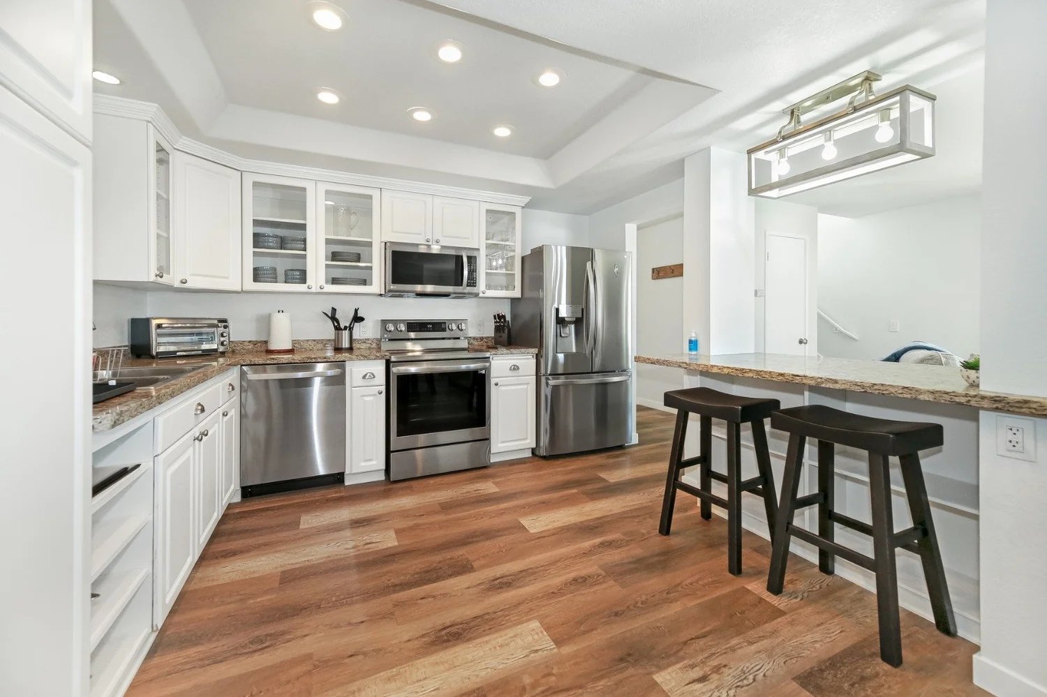 Custom kitchen interior design with white cabinetry, stainless appliances, and stone counters
